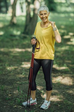 İskandinav yürüyüş egzersizi. Aktif olgun bir kadın doğanın tadını çıkarıyor.