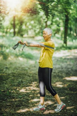 Direniş bandı yürüme egzersizi. Olgun bir kadın elastik direniş bandıyla güç çalışması yapıyor. 