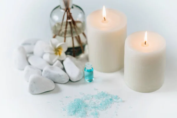 Aromatherapy scented white candles, essential oil reed diffusers and blue sea salt on a white background.