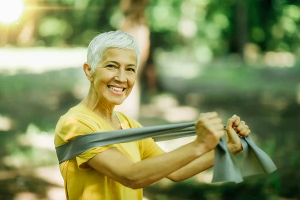 Resistance band walking exercise. Mature woman doing strength workout with elastic resistance band