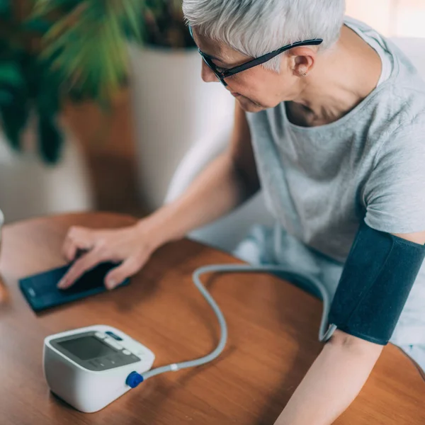 Saúde Móvel Senior Woman Measuring Blood Pressure Entering Data Smart — Fotografia de Stock