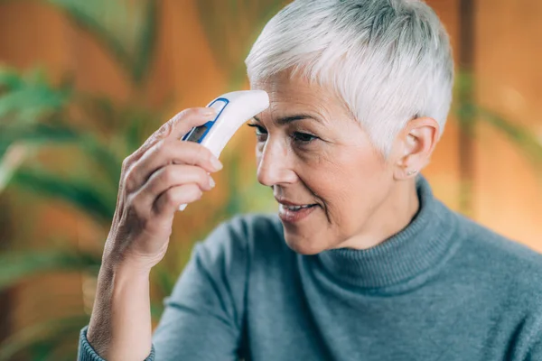 Senior Vrouw Meten Lichaamstemperatuur Met Contactloze Digitale Thermometer Thuis — Stockfoto