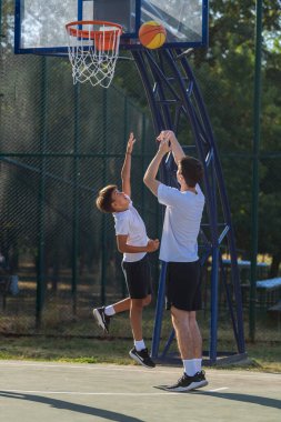 Outdoor basketball training session for kids, where a dedicated coach works one on one with a young boy, emphasizing personal development, athletic skills, and teamwork