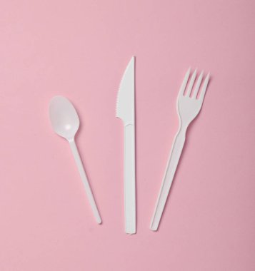 Plastik çatal bıçak takımı pembe bir arka plan üzerinde piknik için. Tek kullanımlık kaşık, çatal, bıçak. Üstten görünüm, kopya alanı