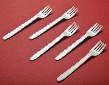 Plastik çatal kırmızı bir arka plan üzerinde piknik için. Minimalist eğilim. Üstten görünüm
