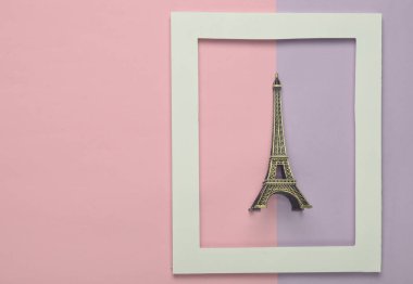 Pastel renkli bir arka plan üzerinde beyaz bir çerçeve Eyfel Kulesi Hatıra heykelciği. Minimalist eğilim. Üstten görünüm