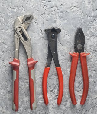 Kerpetenler, ayarlanabilir anahtarı, pense gri beton zemin üzerine. Üstten görünüm