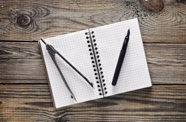 Not defteri, kalem, pergel ahşap bir masa üzerinde. Üstten görünüm.