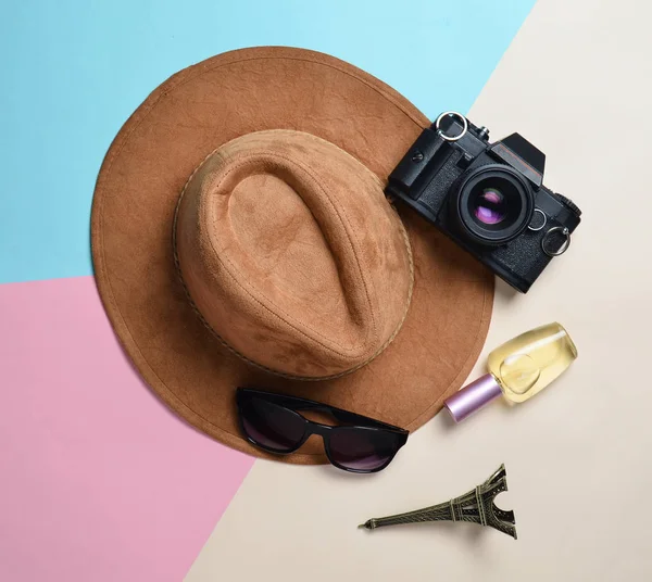 Passion for travel, wanderlust concept. Trip to France, Paris. Felt hat, film camera, sunglasses, perfume bottle, souvenir statue of Eiffel Tower layout on a pastel paper background. Flat lay