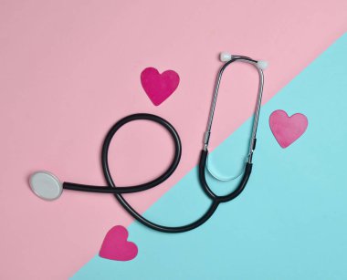 Stetoskop ve pastel renkli arka plan, minimalist eğilim, üstten görünüm dekoratif kalpler, düz yatıyordu. Tıbbi donatımı