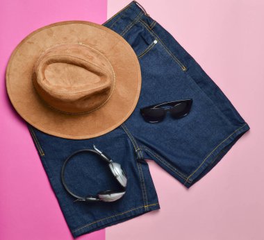 Kağıt arka plan yığını üzerinde Giyim ve moda aksesuarları. Keçe şapka, Gözlük, kulaklık, şort, üstten görünüm, moda bakmak