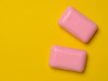 Sabun sarı bir arka plan üzerinde iki pembe dilim. Minimalist eğilim, üstten görünüm, kopya alanı