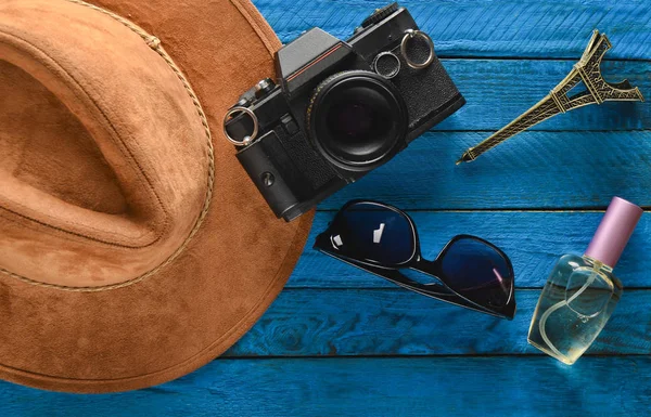Trip to France, Paris. Felt hat, film camera, sunglasses, perfume bottle, souvenir statue of Eiffel Tower layout on a colored wooden background.  Passion for travel, wanderlust concept. Flat lay