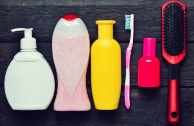 Şişe şampuan, duş jeli, sabun, parfüm, diş fırçası, tarak. Güzellik ve hijyen bakım için ürünler. Siyah ahşap bir masa üzerinde Üstten Görünüm.