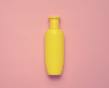 Şampuan pastel pembe bir arka plan üzerinde sarı şişe. Minimalizm eğilimini. Üstten Görünüm. Duş için ürünler. Metin için yer.