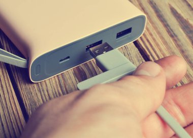 Bir el ahşap arka plan üzerinde bir güç banka a usb tel kablo bağlanır. Harici pil.