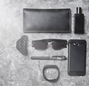 Aksesuar ve gadget'lar için beton yüzeyinde bir iş kadını. Akıllı telefon, akıllı bilezik, kalem, parfüm şişesi, çanta, güneş gözlüğü. Üstten Görünüm. Metin için yer.