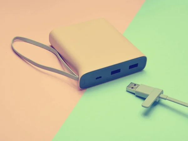 ピンク青のパステル調の背景に Usb ケーブルのクローズ アップでスマート フォンやガジェットを充電用の外部バッテリー 電源銀行 近代的な技術 — ストック写真