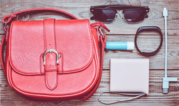 Kırmızı deri çanta ve diğer kadın aksesuarları düzen ahşap bir masa üzerine. Üstten görünüm. Minimalizm eğilimini. Düz yatıyordu.
