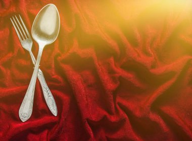 Kaşık ve çatal kırmızı ipek masa örtüsü üzerinde. Vintage çatal bıçak takımı. Uzay kopyalayın. Üstten Görünüm.