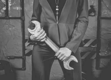 Trendy kıyafetler moda mekanik kız bir İngiliz anahtarı bir otomatik mekanik atölye arka plan üzerinde tutuyor. Moda silah, sıra dışı bir görüntü. Yaşam tarzı.