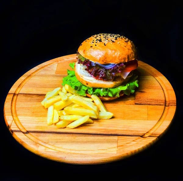 Burger with French fries on a wooden board. Fast food.