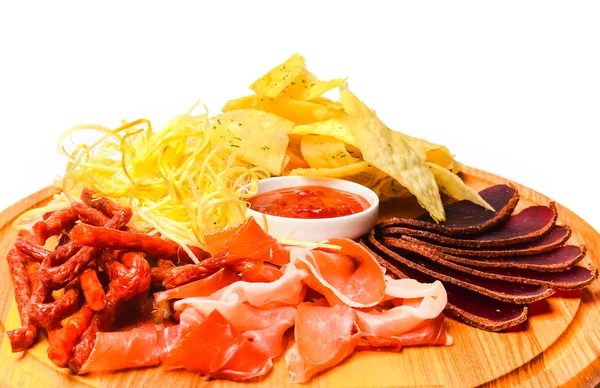 Snack to beer on a wooden board. Basturma, dried meat, dried squid, chips isolated on white background.