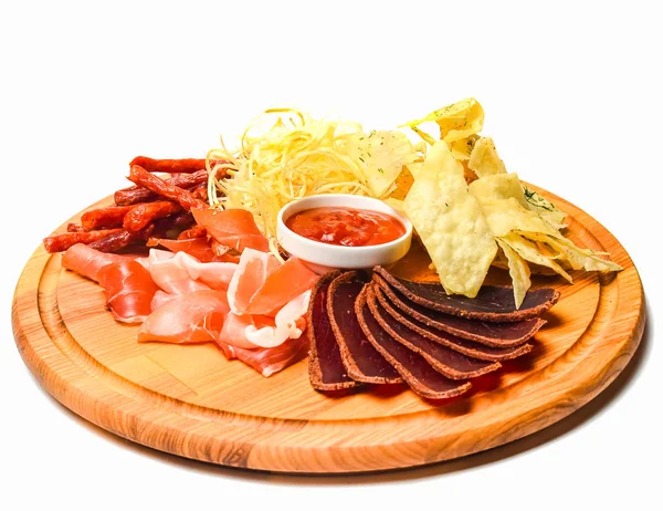 Snack to beer on a wooden board. Basturma, dried meat, dried squid, chips isolated on white background.
