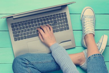Turkuaz ahşap bir masa üzerinde bir dizüstü bilgisayar kullanarak. Üstten Görünüm. Modern gençlik. Nesil z. Online Internet üzerinde çalışma.