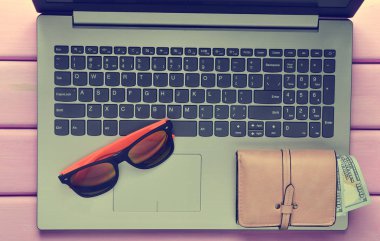 Web iş yerinde bir plaj tesisi kavramı freelancing. Dizüstü bilgisayar, güneş gözlüğü, çanta mor renk ahşap bir masa üzerinde. Üstten görünüm.