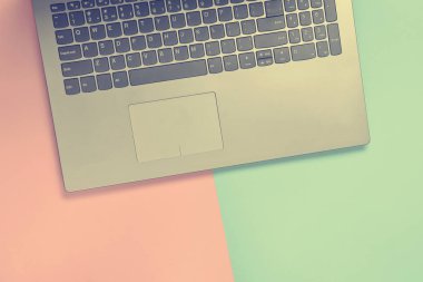 Renkli kağıt arka plan üzerinde bir dizüstü bilgisayar parçası. Klavye, touchpad. Modern dijital teknolojiler. Uzay kopyalayın. Üstten Görünüm.