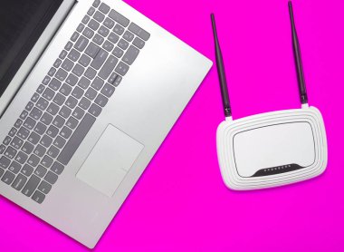 Bir dizüstü bilgisayar ve kablosuz yönlendirici sarı kağıt arka plan üzerinde. Klavye, touchpad. Modern dijital teknolojiler. Uzay kopyalayın. Üstten Görünüm.