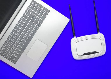 Bir dizüstü bilgisayar ve kablosuz yönlendirici sarı kağıt arka plan üzerinde. Klavye, touchpad. Modern dijital teknolojiler. Uzay kopyalayın. Üstten Görünüm.