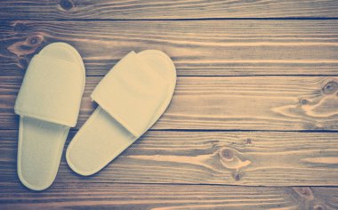 Bir ahşap zemin üzerinde beyaz otel için terlikler. Üstten görünüm.