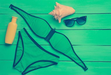 Ahşap arka plan mavi plaj tatil için aksesuarlar. Mayo, Güneş kremi, güneş gözlüğü, kabuk. Üstten görünüm.