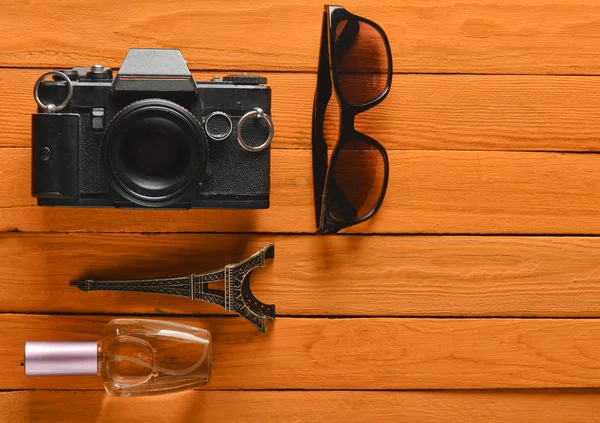 Trip to France, Paris. Film camera, sunglasses, perfume bottle, souvenir statue of Eiffel Tower layout on a colored wooden background.  Passion for travel, wanderlust concept. Flat lay