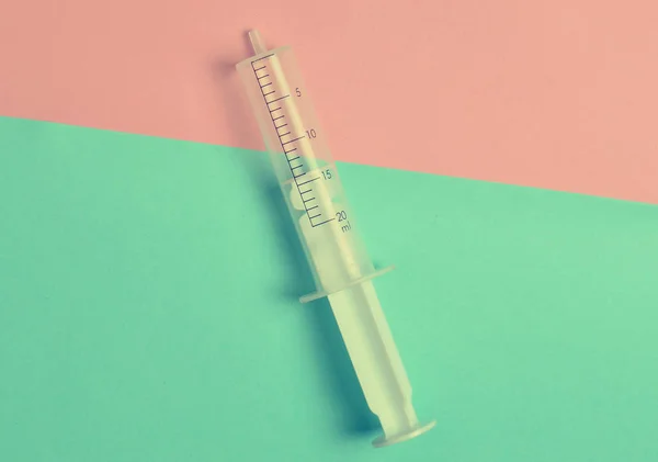 A medical syringe without a needle on a pastel background, top view, minimalism. Medical equipment
