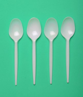 Plastik kaşık yeşil bir arka plan üzerinde piknik için. Üstten görünüm