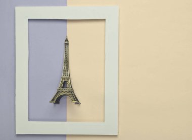 Pastel renkli bir arka plan üzerinde beyaz bir çerçeve Eyfel Kulesi Hatıra heykelciği. Minimalist eğilim. Üstten görünüm