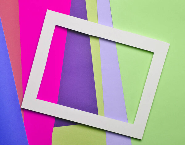 Empty white frame on a multicolored paper background. Copy space