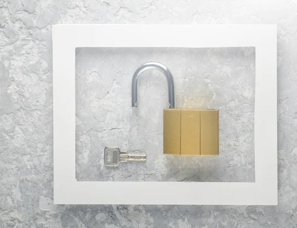 Lock and keys in a white frame on a gray concrete background. Minimalist trend