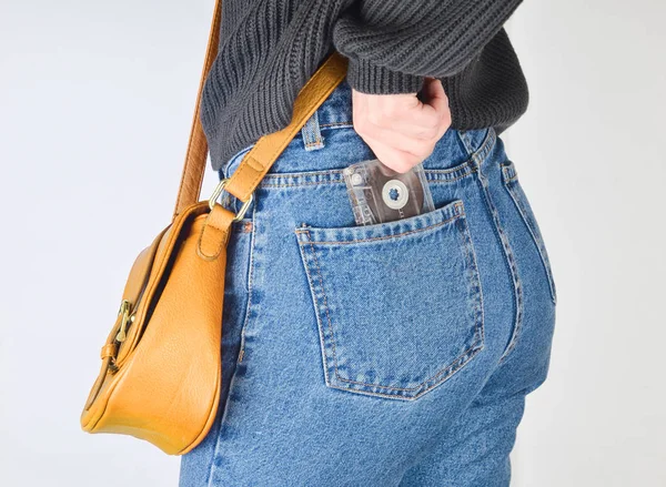 청바지 스웨터에 가장자리에 여자는 바탕에 그녀의 포켓에서 복고풍 오디오 카세트를 — 스톡 사진