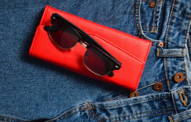 Kadın şeyler ve aksesuarları. Klasik güneş gözlüğü, kırmızı deri çanta, kot pantolon.