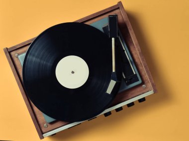 Pastel sarı bir arka plan üzerinde vinil plaka ile Vintage Vinil pikap. Eğlence 70 lerin. Müzik dinlemek. Üstten görünüm.
