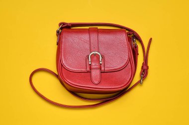Kırmızı deri çanta sarı bir arka plan üzerinde uzun bir kayış üzerinde. Bayan aksesuarlar. Üstten görünüm.