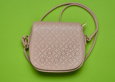 Pastel yeşil bir arka plan üzerinde uzun bir kayış üzerinde bej deri çanta. Bayan aksesuarlar. Üstten görünüm.