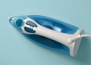 Pastel mavi bir arka plan üzerinde demir. Üstten görünüm. Şeyler Ütü.