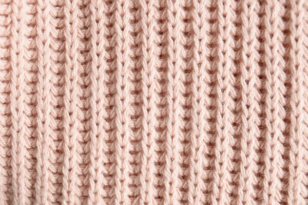 The texture of a pink knitted sweater close-up. Top view. Textile clothing.