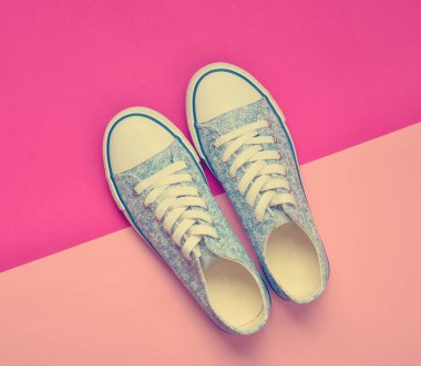 Üzerinden 80s pastel pembe bir arka plan üzerinde beyaz dantel ile klasik kadın spor ayakkabı. Üstten görünüm.