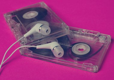Retro teknoloji. Plastik şeffaf ses kaseti ve parlak pembe bir arka plan üzerinde beyaz vakum kulaklık. 80s.